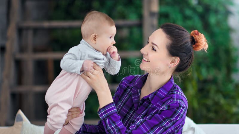 Lächelnde interessierende junge schöne Mutter der mittleren Nahaufnahme, die mit nettem kleinem Baby spielt und täuscht