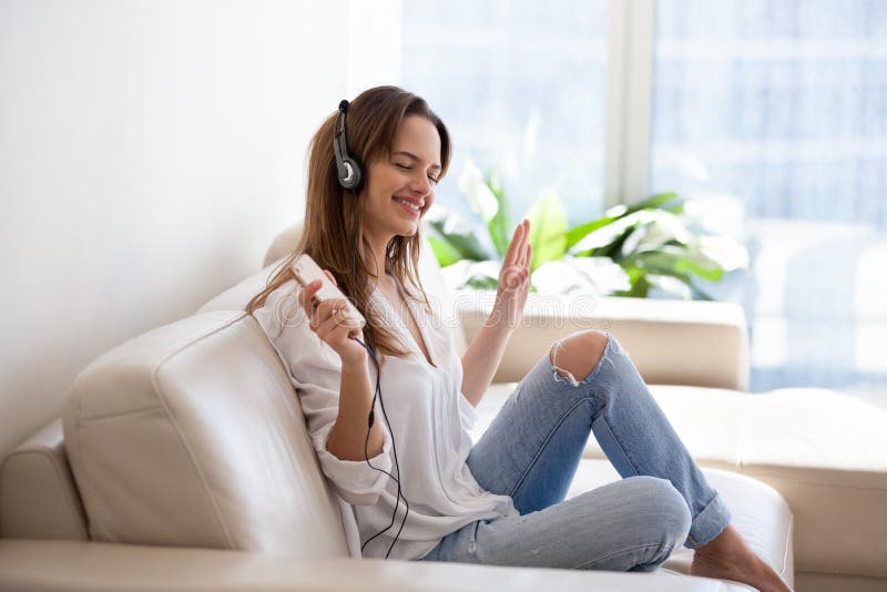 Lächelnde junge Frau in den Kopfhörern hörend Musik auf smartpho
