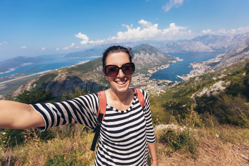 Lächelnde junge Frau nimmt ein selfie auf Hintergrundberg und -meer stockfoto Lächelnde junge Frau nimmt ein selfie auf Hintergrundberg und -meer stockfoto