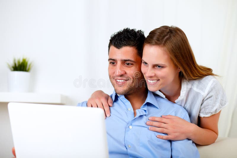 Lächelnde junge Paare unter Verwendung des Laptops