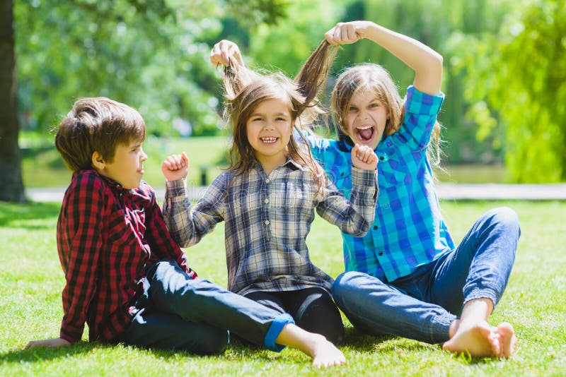 Lächelnde Kinder, die Spaß am Gras haben Kinder, die draußen im Sommer spielen Jugendliche teilen im Freien mit stockfotografie Lächelnde Kinder, die Spaß am Gras haben Kinder, die draußen im Sommer spielen Jugendliche teilen im Freien mit stockfotografie