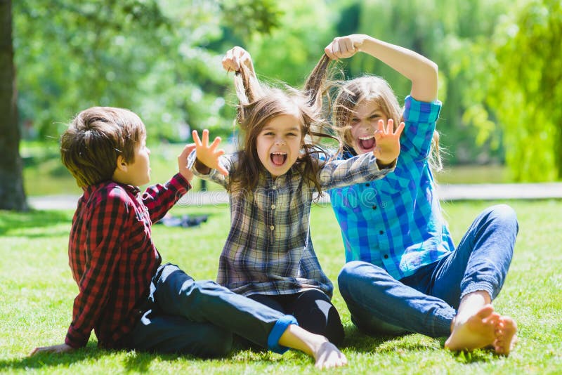 Lächelnde Kinder, die Spaß am Gras haben Kinder, die draußen im Sommer spielen Jugendliche teilen im Freien mit stockbilder Lächelnde Kinder, die Spaß am Gras haben Kinder, die draußen im Sommer spielen Jugendliche teilen im Freien mit stockbilder