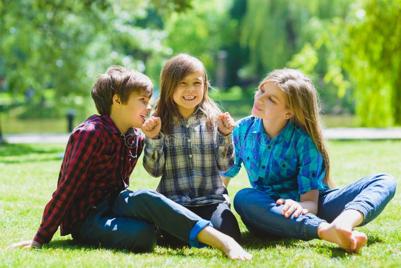 Lächelnde Kinder, die Spaß am Gras haben Kinder, die draußen im Sommer spielen Jugendliche teilen im Freien mit lizenzfreies stockbild Lächelnde Kinder, die Spaß am Gras haben Kinder, die draußen im Sommer spielen Jugendliche teilen im Freien mit lizenzfreies stockbild
