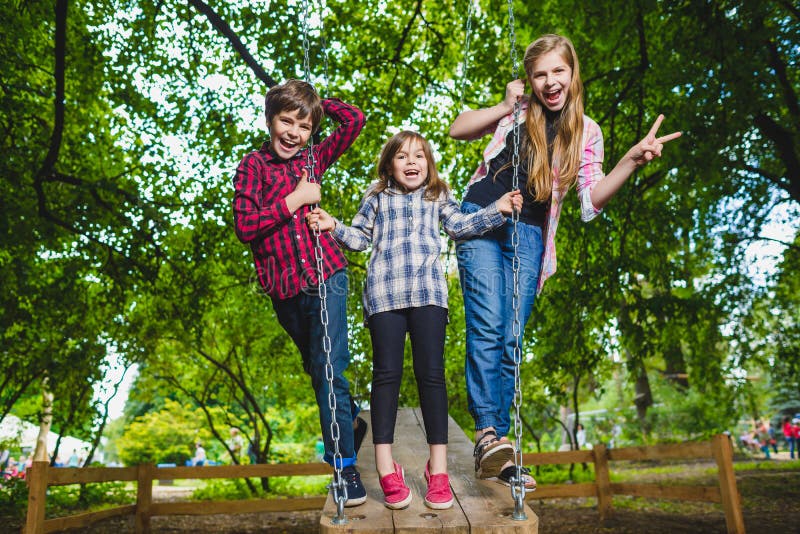 Lächelnde Kinder, die Spaß am Spielplatz haben Kinder, die draußen im Sommer spielen Jugendliche, die draußen auf ein Schwingen f stockbild Lächelnde Kinder, die Spaß am Spielplatz haben Kinder, die draußen im Sommer spielen Jugendliche, die draußen auf ein Schwingen f stockbild