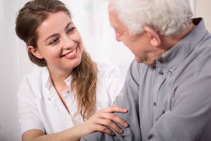 Lächelnde Krankenschwester, die älteren Mann unterstützt