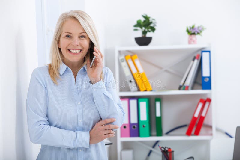 Lächelnde Mitte alterte den Geschäftsmann, der am Telefon im Büro spricht stockfotografie Lächelnde Mitte alterte den Geschäftsmann, der am Telefon im Büro spricht stockfotografie