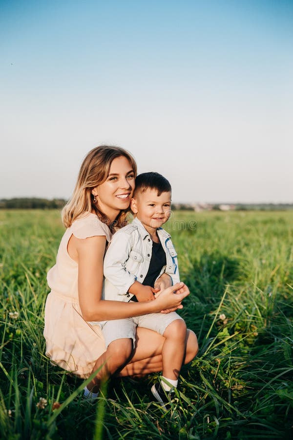 Lächelnde Mutter und Baby, die auf Wiese sitzen lizenzfreie stockfotos Lächelnde Mutter und Baby, die auf Wiese sitzen lizenzfreie stockfotos