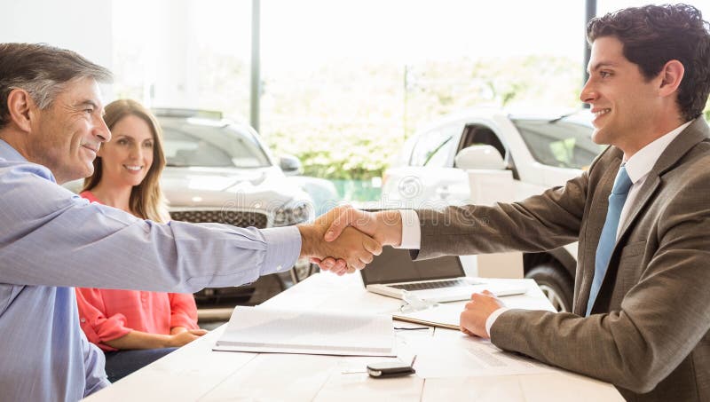 Smiling couple buying a new car at new car showroom. Smiling couple buying a new car at new car showroom