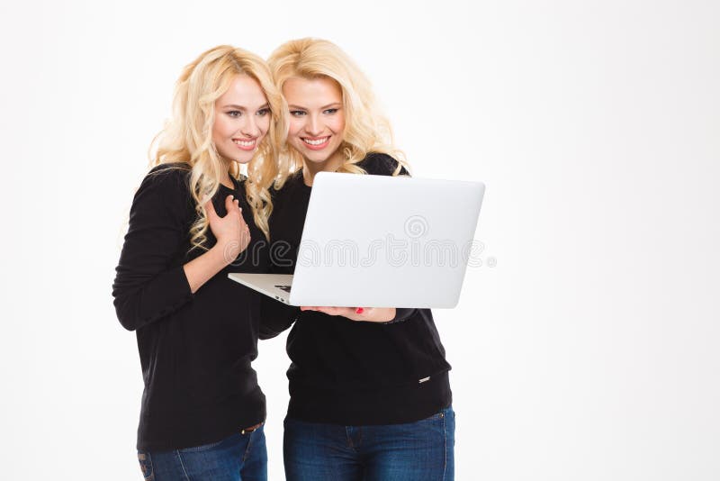 Lächelnde Schwesterzwillinge unter Verwendung der Laptopberechnung stockfotos Lächelnde Schwesterzwillinge unter Verwendung der Laptopberechnung stockfotos
