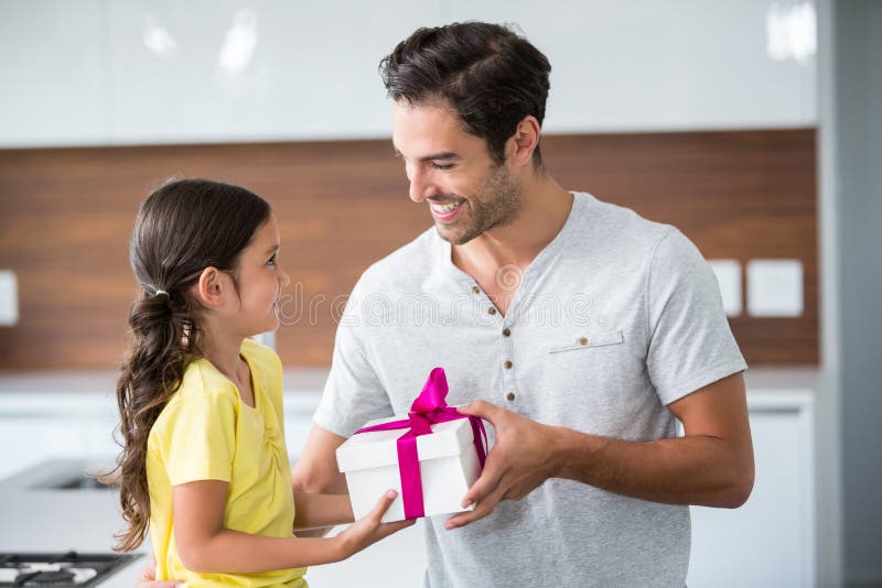 Lächelnde Tochter, die dem Vater Geschenkbox gibt lizenzfreies stockfoto Lächelnde Tochter, die dem Vater Geschenkbox gibt lizenzfreies stockfoto