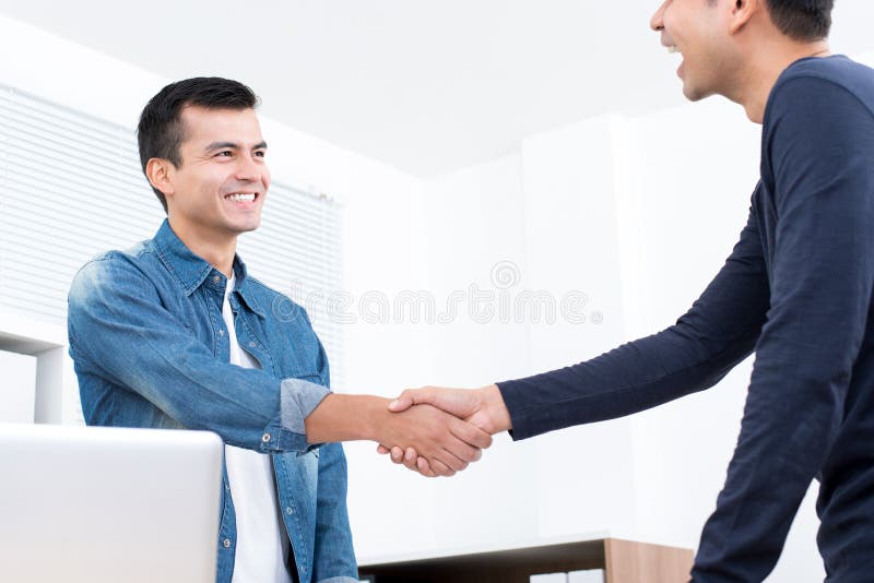 Lächelnde zufällige Geschäftsmänner, die Händedruck im Büro machen stockfoto Lächelnde zufällige Geschäftsmänner, die Händedruck im Büro machen stockfoto