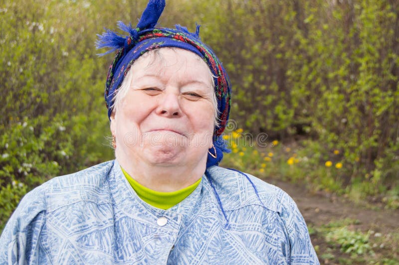 Lächelnde ältere Frau in einem Kopftuch in Ihrem Garten lizenzfreie stockfotos Lächelnde ältere Frau in einem Kopftuch in Ihrem Garten lizenzfreie stockfotos
