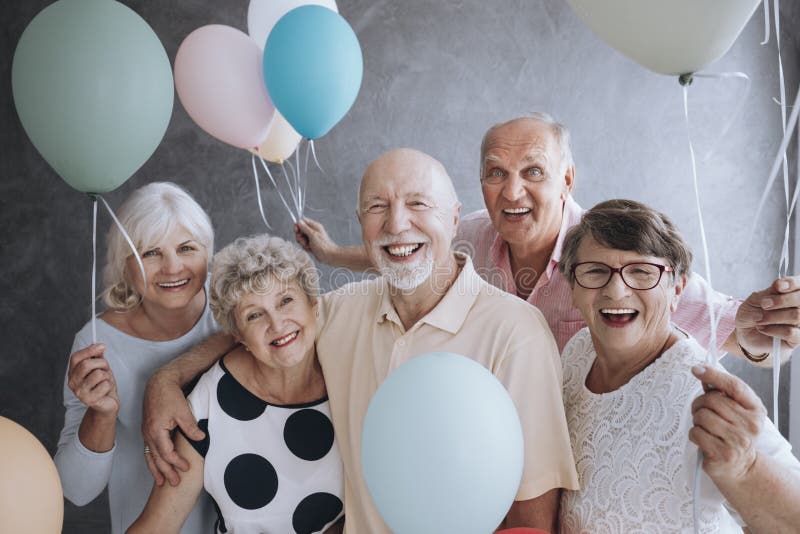 Lächelnde ältere Freunde mit bunten Ballonen das Treffen genießend stockfotos Lächelnde ältere Freunde mit bunten Ballonen das Treffen genießend stockfotos