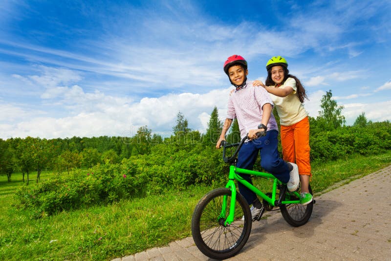 Lächelnder afrikanischer Junge und Mädchen, die das gleiche Fahrrad reiten lizenzfreie stockfotos Lächelnder afrikanischer Junge und Mädchen, die das gleiche Fahrrad reiten lizenzfreie stockfotos