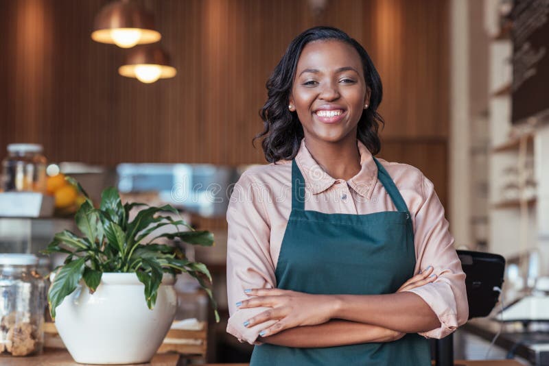 Lächelnder afrikanischer Unternehmer, der am Zähler ihres Cafés steht