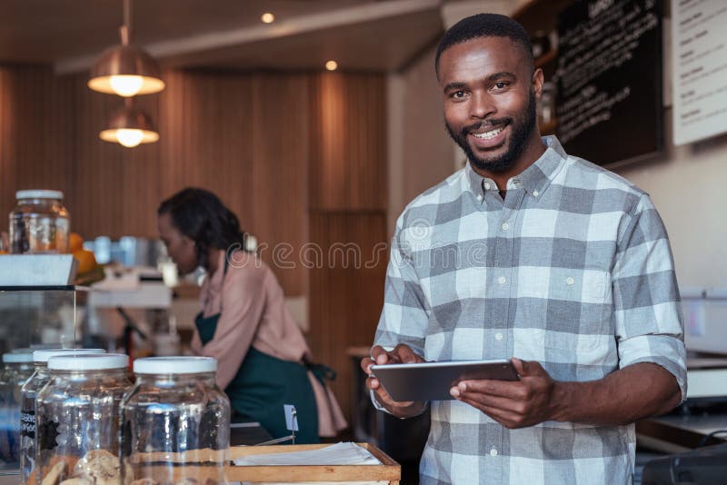 Lächelnder afrikanischer Unternehmer, der am Zähler seines Cafés arbeitet