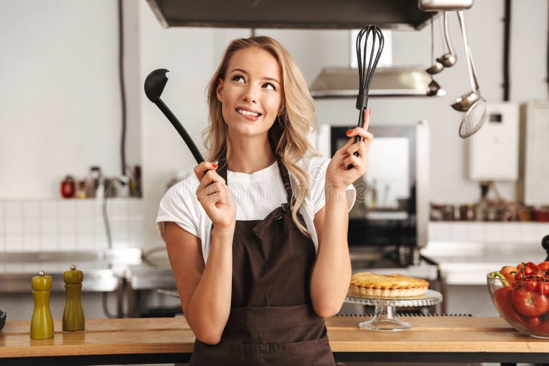 Lächelnder Chefkoch der jungen Frau im Schutzblech lizenzfreies stockbild Lächelnder Chefkoch der jungen Frau im Schutzblech lizenzfreies stockbild