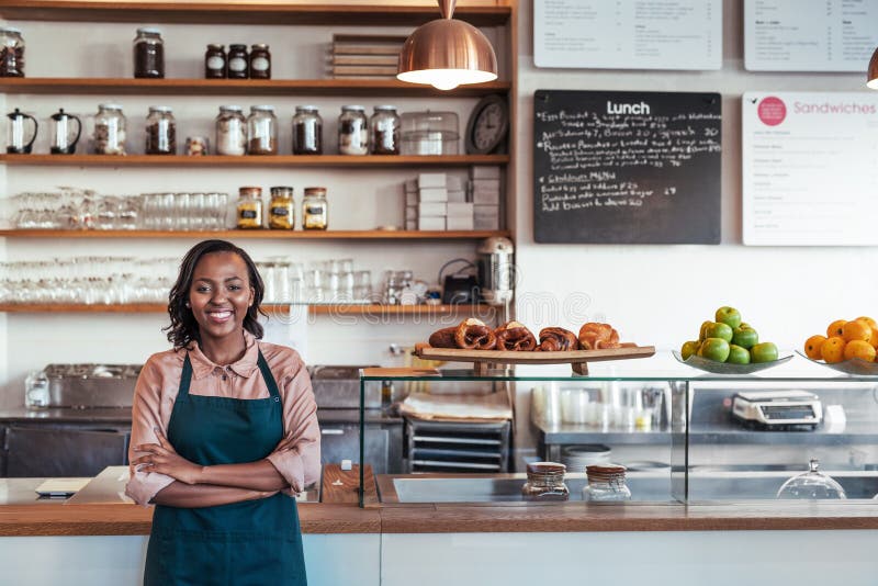 Lächelnder junger afrikanischer Unternehmer, der an ihrem Bäckereizähler steht