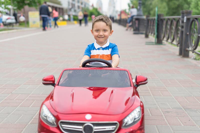Lächelnder kleiner Junge, der mit dem Spielzeugauto fährt Aktive Freizeit und Sport für Kinder Porträt des glücklichen Kleinkinde lizenzfreie stockfotografie Lächelnder kleiner Junge, der mit dem Spielzeugauto fährt Aktive Freizeit und Sport für Kinder Porträt des glücklichen Kleinkinde lizenzfreie stockfotografie