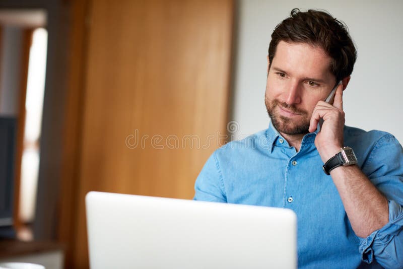 Lächelnder Mann, der auf einem Mobiltelefon beim Arbeiten vom Haus spricht lizenzfreie stockfotos Lächelnder Mann, der auf einem Mobiltelefon beim Arbeiten vom Haus spricht lizenzfreie stockfotos