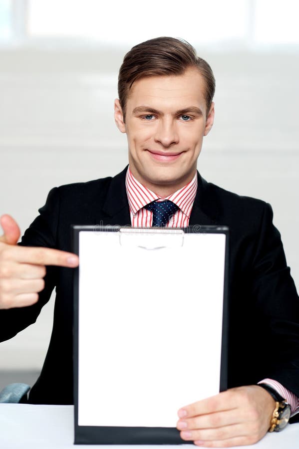 Lächelnder Mann, der in Richtung zum unbelegten Klemmbrett zeigt lizenzfreies stockbild