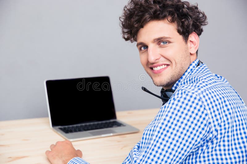 Lächelnder Mann, der am Tisch mit Laptop sitzt
