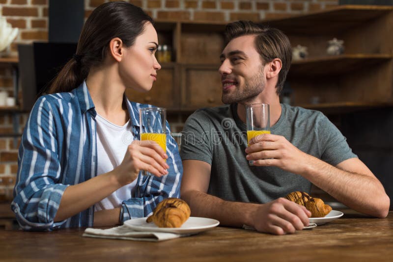 Lächelnder Mann und trinkender Saft und Essen der Frau von Hörnchen stockfotos