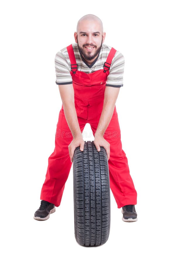 Lächelnder Mechaniker, der auf einem Neuwagenrad stillsteht stockbilder Lächelnder Mechaniker, der auf einem Neuwagenrad stillsteht stockbilder