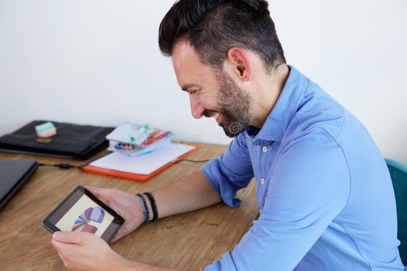 Lächelnder reifer Geschäftsmann, der digitale Tablette am Schreibtisch verwendet stockfotografie Lächelnder reifer Geschäftsmann, der digitale Tablette am Schreibtisch verwendet stockfotografie