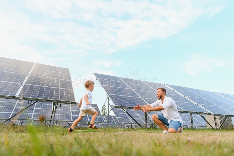Lächelnder Vater und sein kleines Kind auf dem Hintergrund von Solarzellen. junger Vater verbringt gerne Zeit mit seinem Sohn. glü lizenzfreie stockfotos