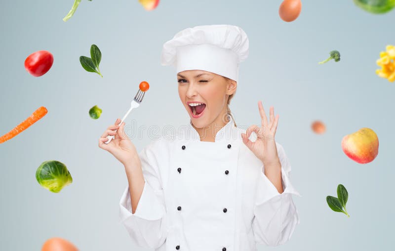 Lächelnder weiblicher Chef mit Gabel und Tomate lizenzfreies stockfoto Lächelnder weiblicher Chef mit Gabel und Tomate lizenzfreies stockfoto