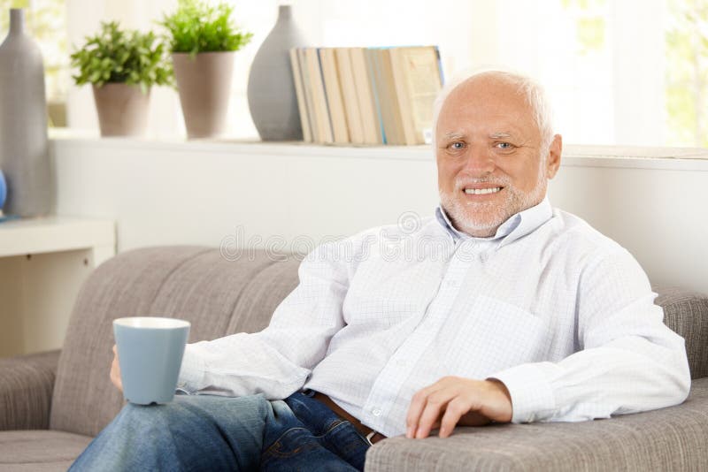 Smiling elderly man having coffee at home, sitting on sofa, looking at camera. Smiling elderly man having coffee at home, sitting on sofa, looking at camera.