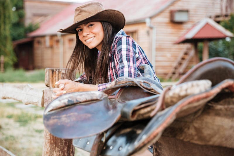 Lächelndes Cowgirl der jungen Frau des Brunette, das auf Zaun im Dorf sich lehnt stockfotos Lächelndes Cowgirl der jungen Frau des Brunette, das auf Zaun im Dorf sich lehnt stockfotos