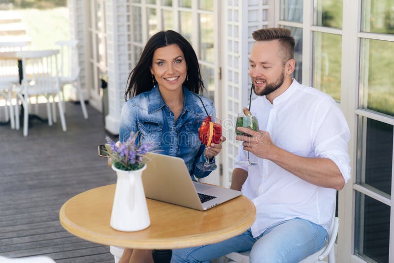 Lächelndes herzliches Mädchen, das an einem Tisch in einem Café mit ihrem Freund, breit lächelnd aufwirft Alte Freunde schließlic lizenzfreies stockbild Lächelndes herzliches Mädchen, das an einem Tisch in einem Café mit ihrem Freund, breit lächelnd aufwirft Alte Freunde schließlic lizenzfreies stockbild