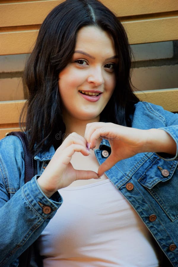 Lächelndes junges Mädchen macht Herz mit den Fingern lizenzfreie stockfotos Lächelndes junges Mädchen macht Herz mit den Fingern lizenzfreie stockfotos
