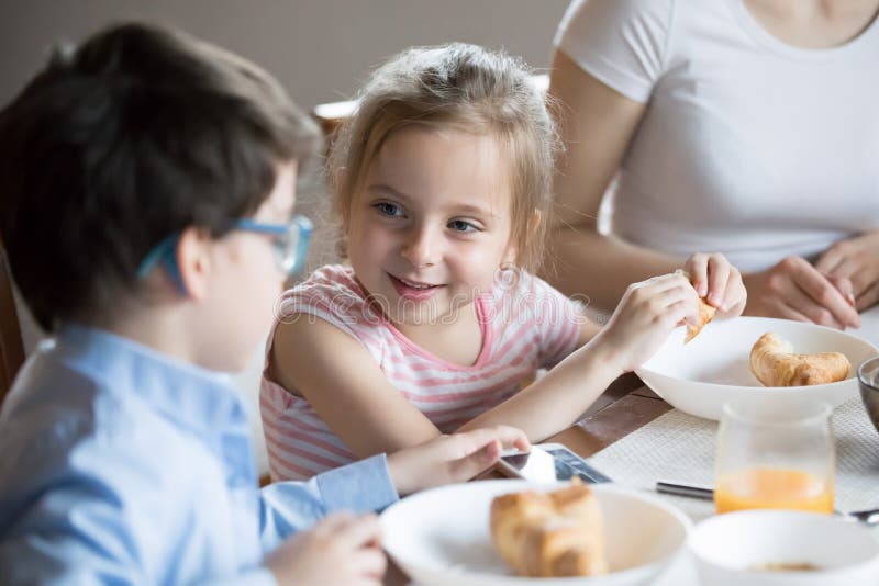 Lächelndes kleines Mädchen, das zu Hause mit Bruder am Frühstück spricht lizenzfreies stockfoto