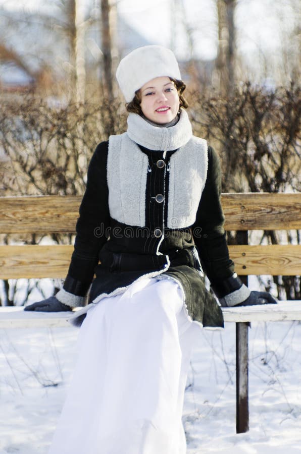 Lächelndes Mädchen auf einer Bank im Winter parken stockbild Lächelndes Mädchen auf einer Bank im Winter parken stockbild