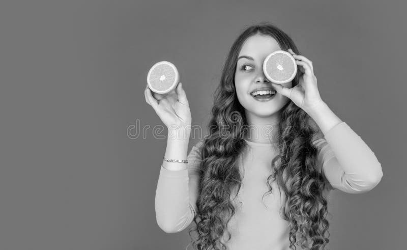 Lächelndes Mädchen hält orangefarbene Früchte auf rosa Untergrund lizenzfreies stockfoto