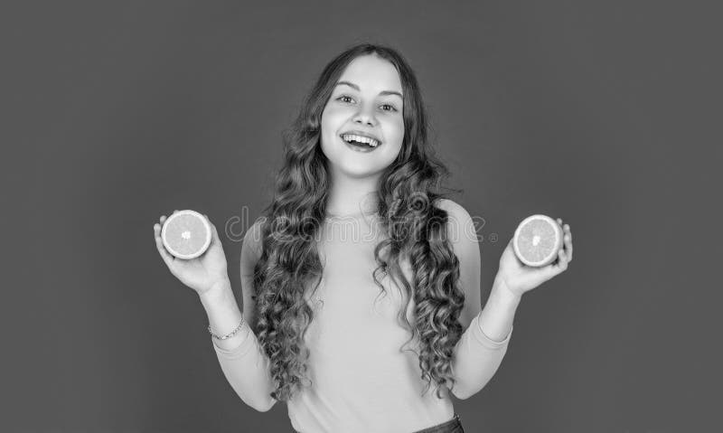 Lächelndes Mädchen hält orangefarbene Früchte auf violettem Hintergrund stockbilder