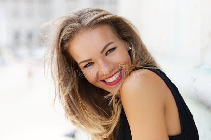 Lächelndes Porträt der glücklichen jungen sorglosen Frau im Freien