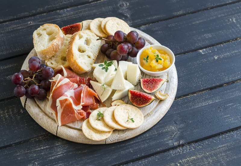 Läcker aptitretare till vin - skinka, ost, druvor, smällare, fikonträd, muttrar, driftstopp, tjänade som på ett ljust träbräde arkivbild Läcker aptitretare till vin - skinka, ost, druvor, smällare, fikonträd, muttrar, driftstopp, tjänade som på ett ljust träbräde arkivbild