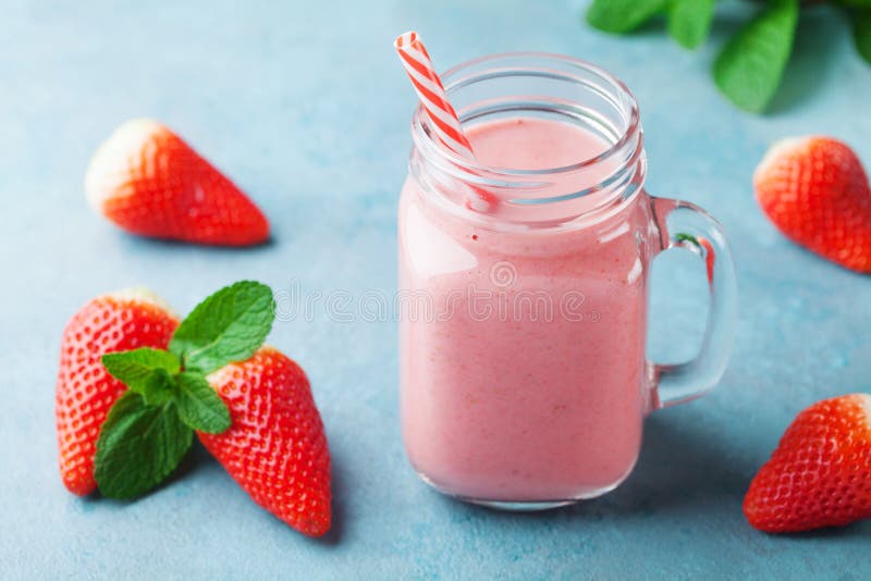 Läcker jordgubbesmoothie eller milkshake i murarekrus på turkostabellen Sund mat för frukost och mellanmål arkivfoto