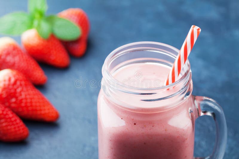 Läcker jordgubbesmoothie eller milkshake i murarekruset på mörker - blå tabell Sund mat för frukost och mellanmål arkivfoton