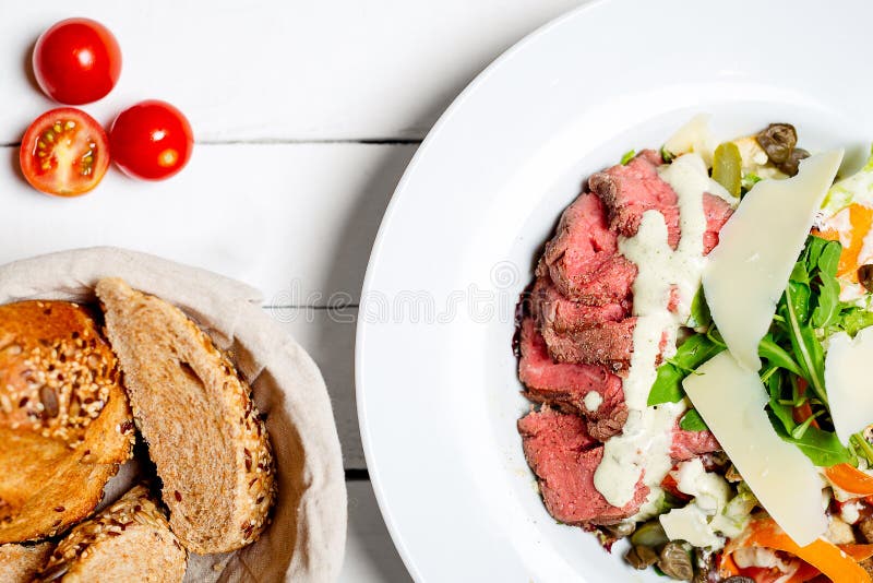 Läcker köttnötköttbiff som lagas mat på medelsällsynt stek och tjänas som med sallad och ost för ny grönsak arkivbilder Läcker köttnötköttbiff som lagas mat på medelsällsynt stek och tjänas som med sallad och ost för ny grönsak arkivbilder