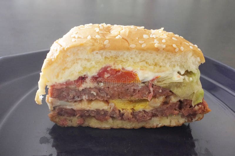 Läckra hamburgare med nötkött, tomaten och ost, avsnittsiktshamburgare fotografering för bildbyråer Läckra hamburgare med nötkött, tomaten och ost, avsnittsiktshamburgare fotografering för bildbyråer