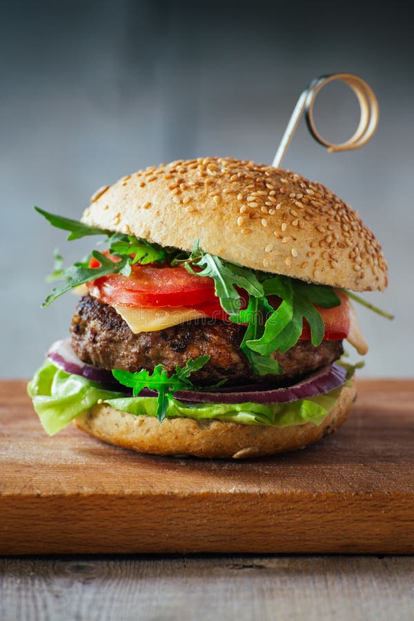 Läckra hamburgare med nötkött, tomaten, ost och grönsallat royaltyfria bilder Läckra hamburgare med nötkött, tomaten, ost och grönsallat royaltyfria bilder