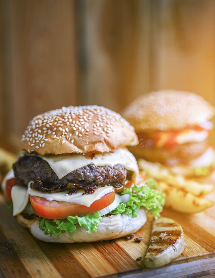 Läckra hamburgare med nötkött, tomaten, ost och grönsallat arkivfoton Läckra hamburgare med nötkött, tomaten, ost och grönsallat arkivfoton