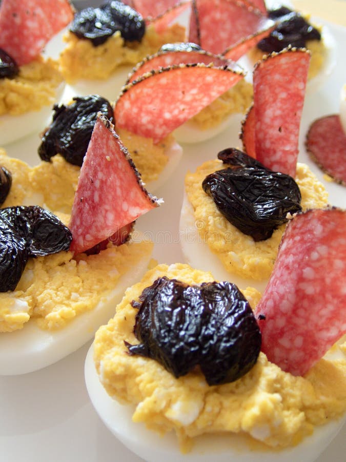 Läckra välfyllda kokta halva ägg med olik fyllningäggula som är blandad med ost- eller leverpate och dekorerat med salami och bla arkivfoto Läckra välfyllda kokta halva ägg med olik fyllningäggula som är blandad med ost- eller leverpate och dekorerat med salami och bla arkivfoto