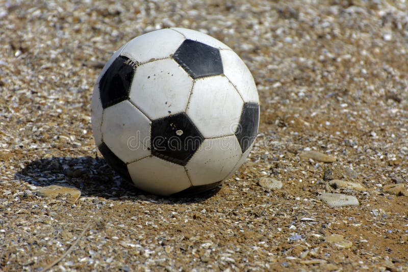 Läderfotbollbollen ligger på bakgrunden av den sandiga stranden S royaltyfri fotografi Läderfotbollbollen ligger på bakgrunden av den sandiga stranden S royaltyfri fotografi