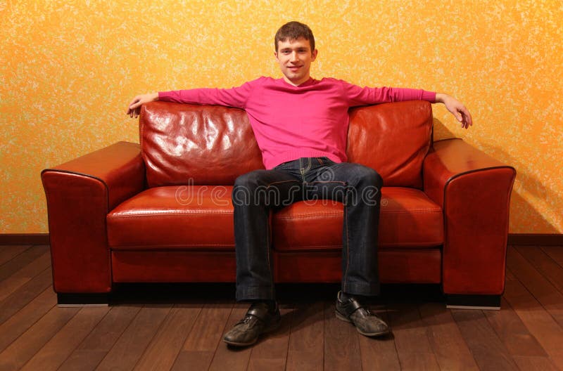 Lädermanred sitter sofaen royaltyfri bild
